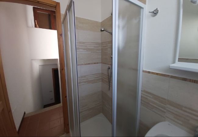 Bagno con box doccia e pareti piastrellate.