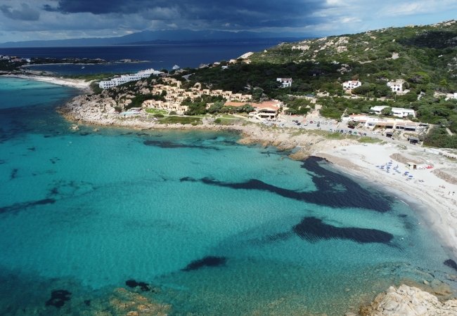 Spiaggia e mare turchese con colline.