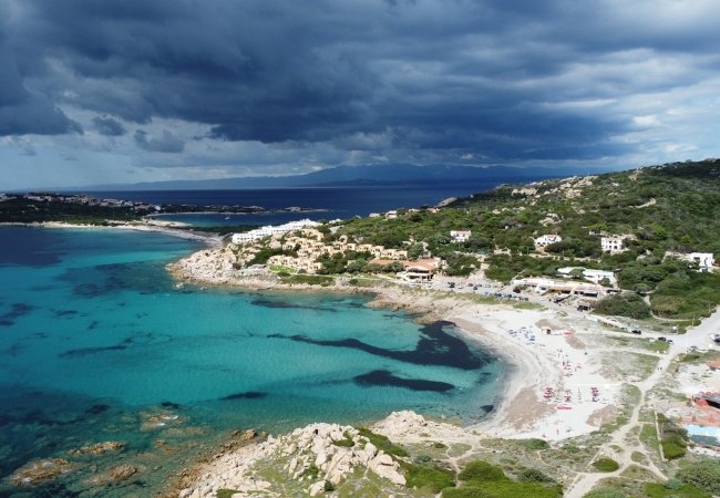 Spiaggia con acque turchesi e cielo nuvoloso.