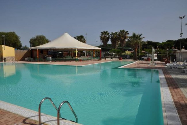 Piscina all'aperto con tenda a cupola bianca sullo sfondo e palme vicino.