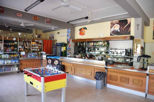 Interno di un bar con bancone e calcetto.