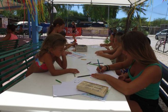 Bambini al tavolo all'aperto colorano e disegnano con pastelli.