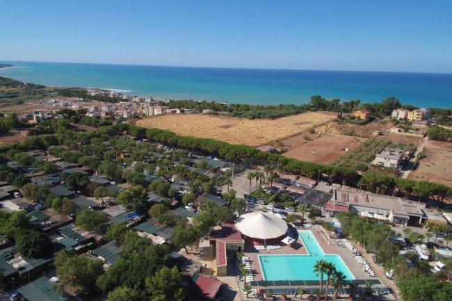 Veduta aerea di un villaggio turistico con piscine vicino alla costa.