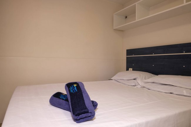 Camera da letto minimalista con un letto matrimoniale e asciugamani blu scuro.