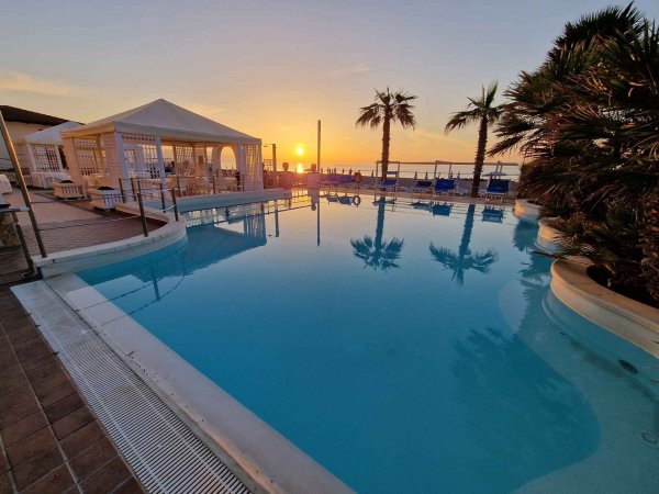 Piscina con palme al tramonto.