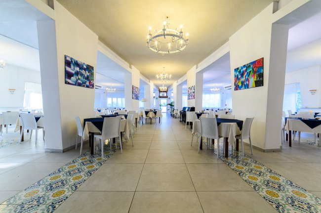 Grande sala con tavoli, decorazioni moderne e lampadari.