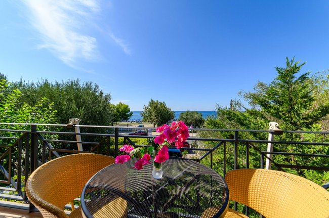 Balcone con tavolo, sedie e vista sul mare.