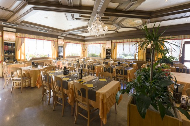 Sala da pranzo elegante con tavoli apparecchiati e grandi finestre.