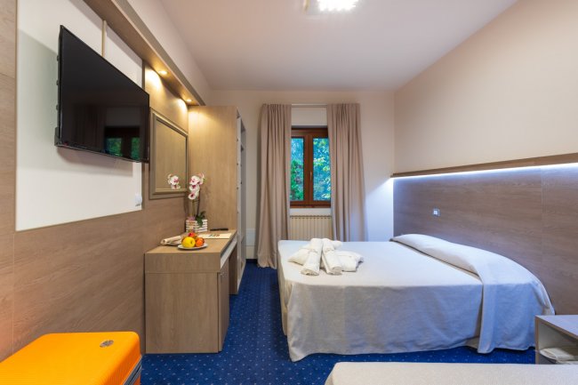 Camera d'hotel moderna con letto matrimoniale e TV a schermo piatto.