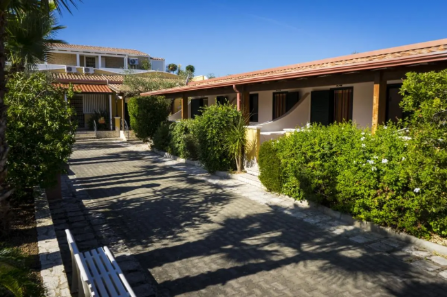 Un viale esterno con cespugli e villette a schiera.