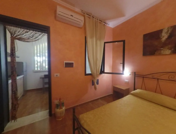 Camera da letto con pareti arancioni, letto matrimoniale, finestra aperta e condizionatore d'aria.