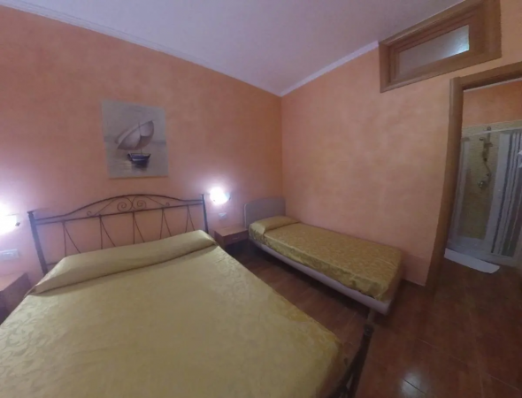 Camera da letto con pareti arancioni, un letto matrimoniale e un letto singolo.