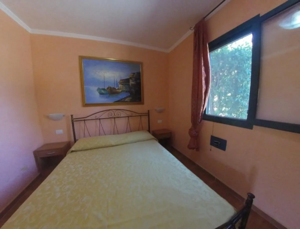 Camera da letto con letto matrimoniale, quadro e finestra.