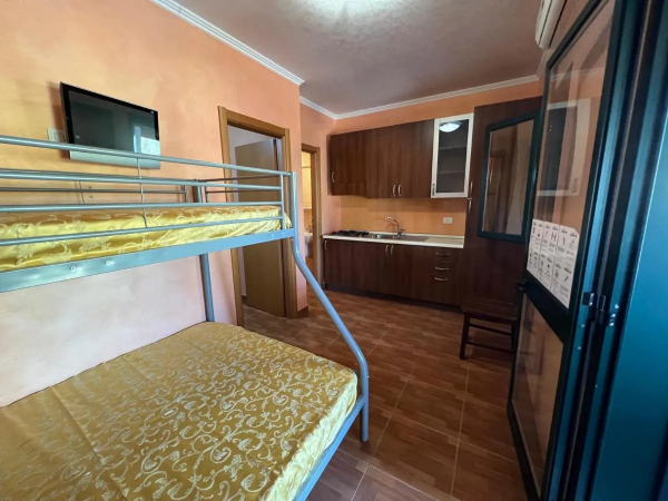 Camera con letto a castello, cucina compatta, pareti arancioni.