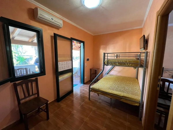 Camera con letto a castello, pareti arancioni, condizionatore e porta finestra.
