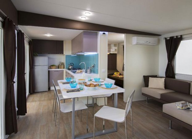 Interno moderno con cucina, tavolo apparecchiato e divano.