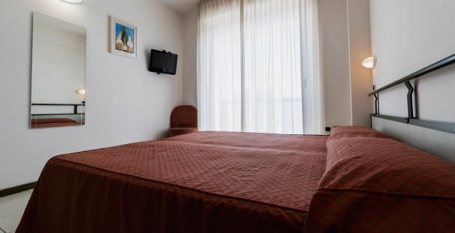 Stanza con letto matrimoniale e TV a parete.