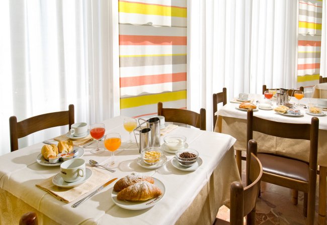 Tavola apparecchiata con colazione e succhi di frutta.