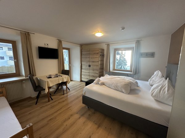 Camera con letto matrimoniale e tavolo, pavimento in legno.