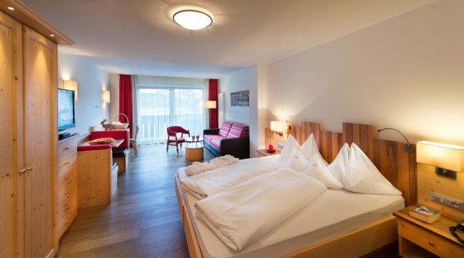 Camera d'hotel con letto matrimoniale e arredamento in legno.