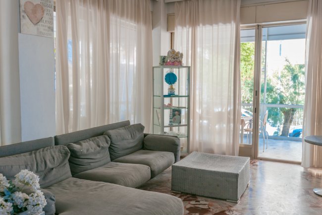 Salotto con divano grigio e grandi finestre luminose.