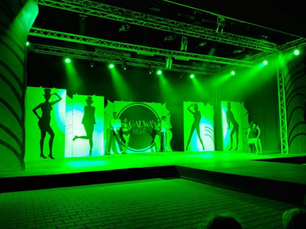 Palco con luci verdi e silhouette.