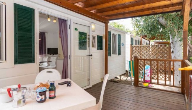 Terrazza con tavolo apparecchiato e sedie bianche.