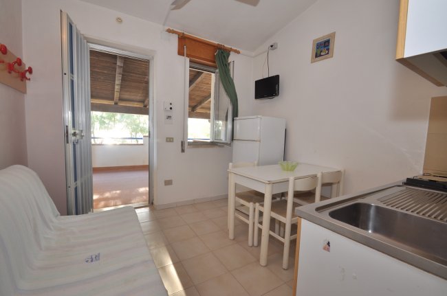 Piccola cucina con tavolo bianco e divano.