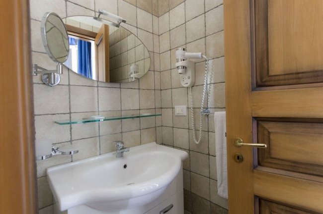 Bagno con lavabo bianco e specchio ovale.