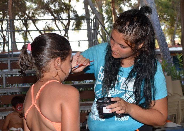 Donna dipinge il volto di una bambina.