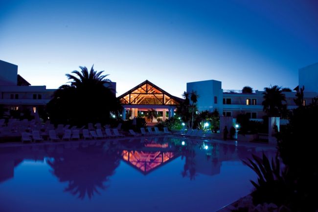 Resort illuminato al crepuscolo con riflessi in piscina.
