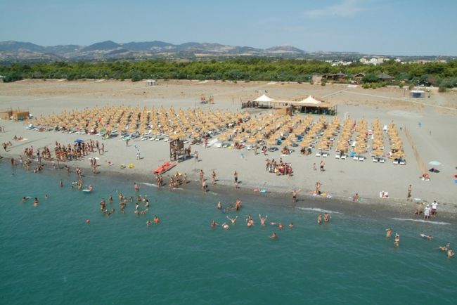 Spiaggia affollata con ombrelloni e bagnanti.