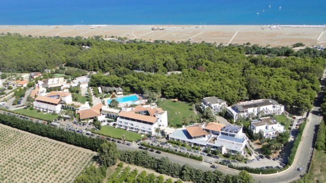 Vista aerea di un resort vicino al mare con piscina e vegetazione.