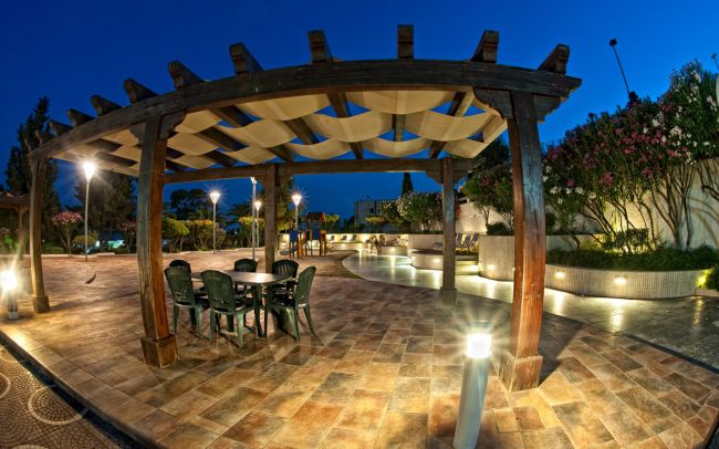 Pergolato con tavolo su terrazza piastrellata di notte.