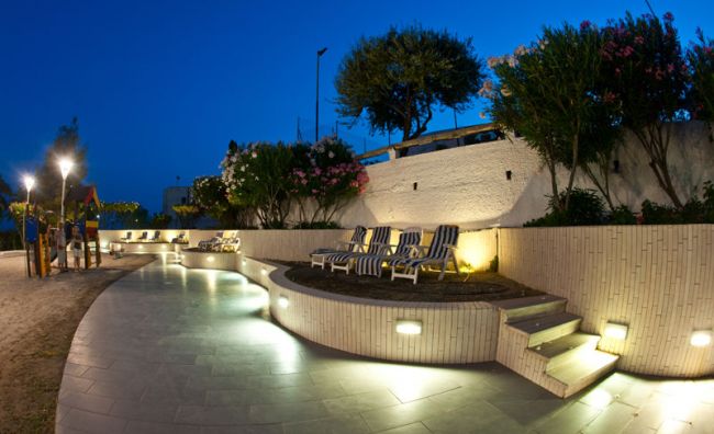 Area relax notturna con sdraio illuminate e piante.