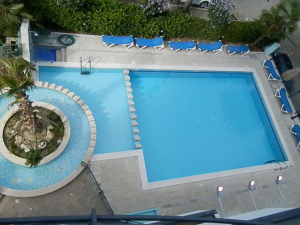 Piscina vista dall'alto con sdraio blu attorno.