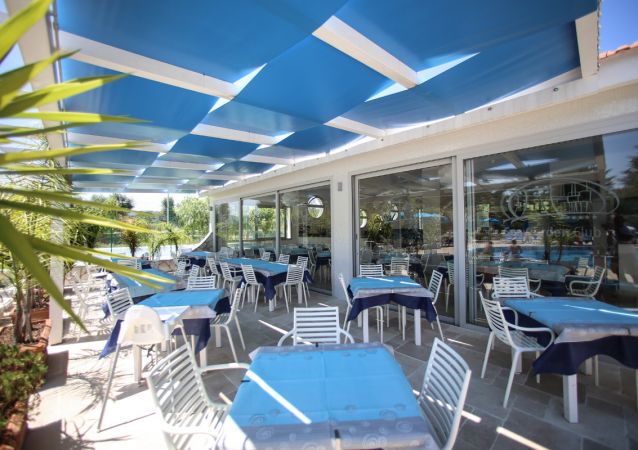 Veranda con tavoli e sedie, coperta da teli blu.