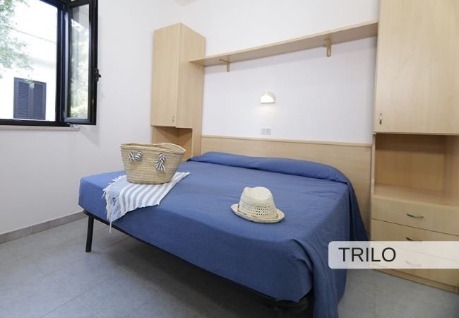 Camera con letto matrimoniale e cappello di paglia sul letto.