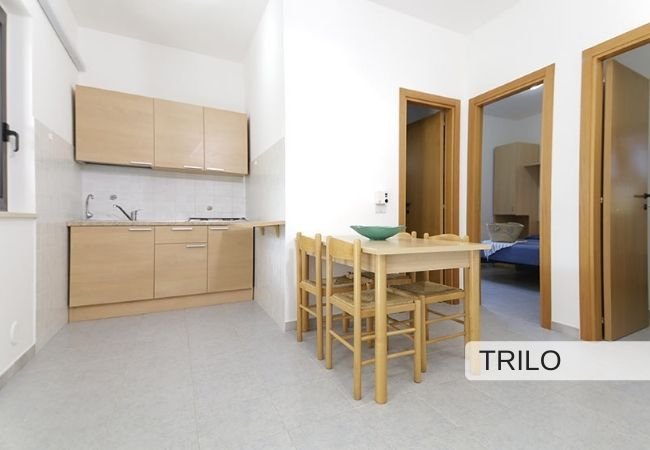 Cucina e soggiorno con tavolo e sedie in legno chiaro.