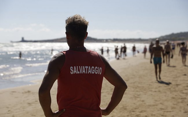 Bagnino sulla spiaggia con maglia rossa 