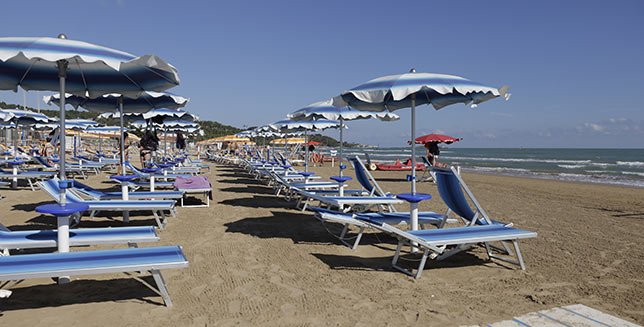 Spiaggia con lettini e ombrelloni blu.