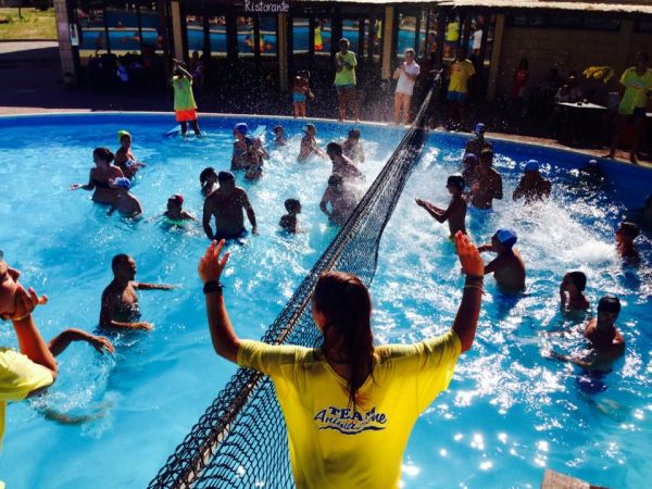 Persone che giocano in piscina con una rete da pallavolo.