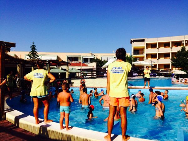Animatori e bambini giocano in piscina all'aperto.