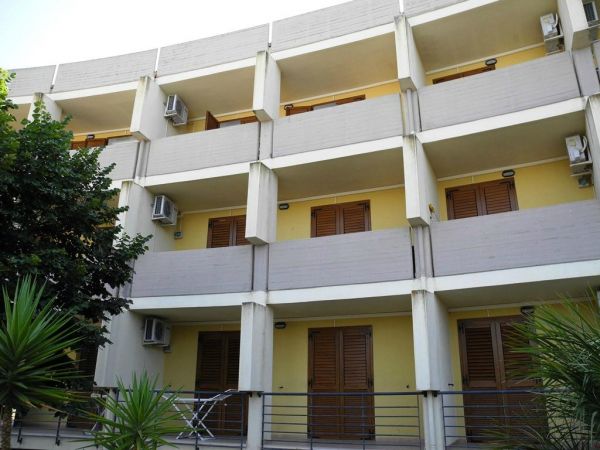 Edificio residenziale con balconi e persiane marroni.
