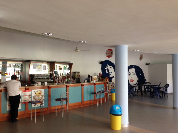 Bancone bar con sedie e decorazioni murali stilizzate.