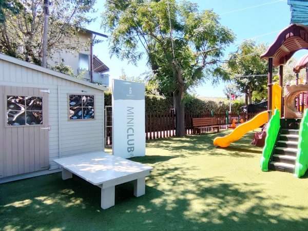 Area giochi con casetta e scivolo per bambini.