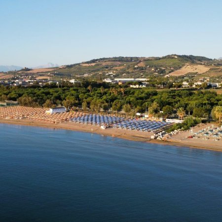 Spiaggia con ombrelloni vista mare e colline sullo sfondo.