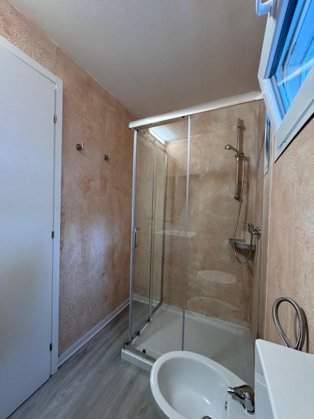 Bagno con doccia in vetro e pareti beige.