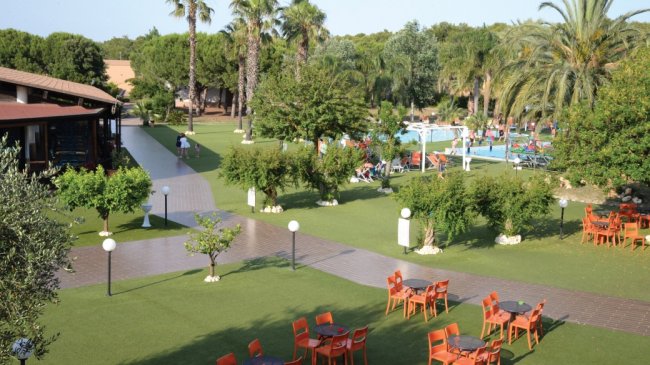 Giardino con piscina e tavoli all'aperto.