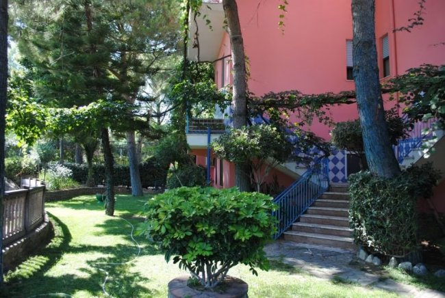 Giardino verde con edificio rosa e scale blu.